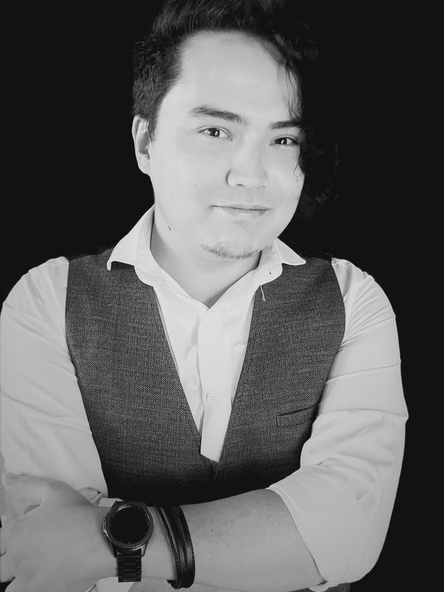 Retrato em preto e branco de Flávio C. Fujita, fundador da The Legal Workshop, de colete e camisa branca, braços cruzados.